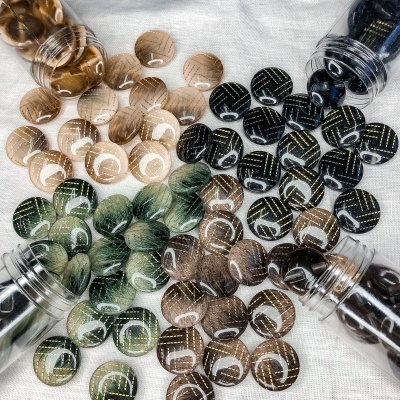 Pérolas redondas coloridas com linhas douradas em superfície branca.