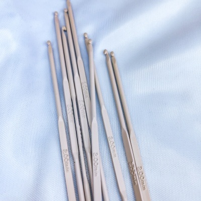 Agulhas de croché metálicas com várias espessuras sobre tecido azul claro