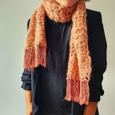 Cachecol felpudo cor de salmão com franjas usado por pessoa com blusa preta