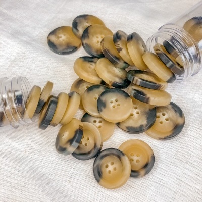 Botões redondos bege com manchas pretas em tecido branco e tubos plásticos.