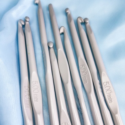 Agulhas de crochet metálicas prateadas com medida 5.00 mm sobre tecido azul claro