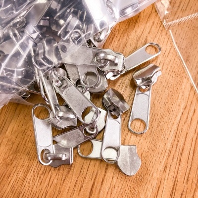 Cursores de zíper metálicos prateados sobre madeira