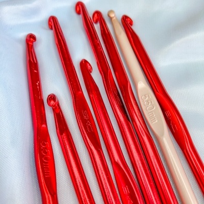 Agulhas de croché vermelhas e bege em tecido branco