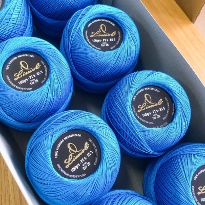 Novelos de linha azul de algodão mercerizado numa caixa de cartão