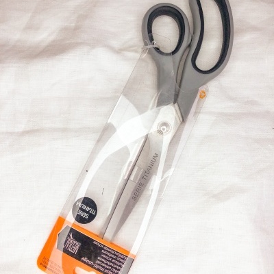 Tesoura com cabo preto e lâminas de aço inoxidável em embalagem plástica transparente