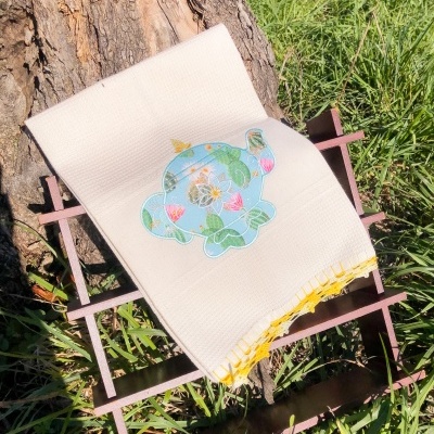 Toalha branca com estampa de elefante colorido, ao ar livre, sobre estrutura metálica