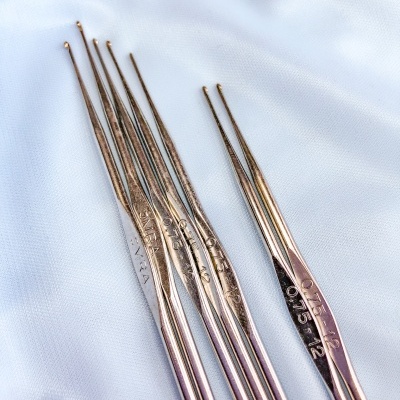 Agulhas de crochet metálicas numeradas sobre tecido branco