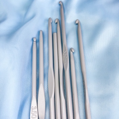 Conjunto de agulhas de crochet cinzentas sobre tecido azul claro