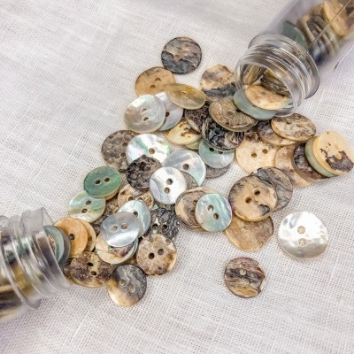 Botões naturais coloridos em tecido branco com dois frascos de vidro.