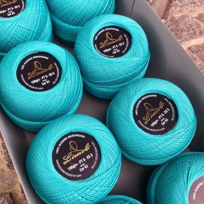 novelos de fio azul-turquesa Linovel numa caixa cinzenta