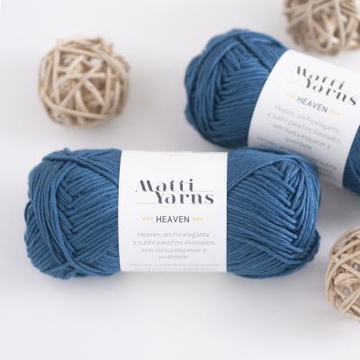 Novelos de lã azul escura com etiquetas Matti Yarns Heaven sobre fundo branco com decoração