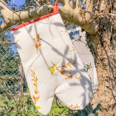 Luva de forno branca com flores amarelas pendurada numa árvore