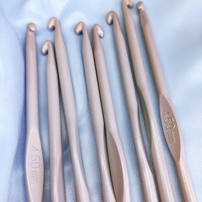 Conjunto de agulhas de crochê rosa claro sobre tecido branco