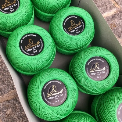 Pacote com nove novelos de linha verde com etiquetas pretas e douradas