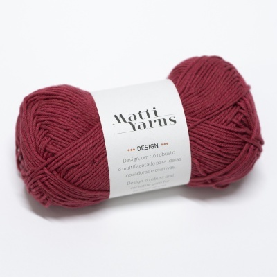 Novelo de lã vermelho escuro com etiqueta etiquetada 'Matti Yarns DESIGN'