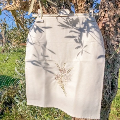 Saia branca com bordado floral pendurada numa árvore ao ar livre