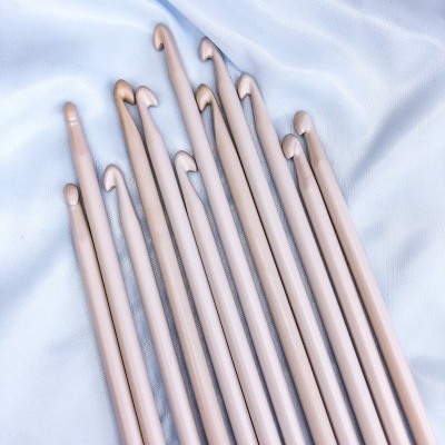 Agochas de croché bege claro de vários tamanhos sobre tecido branco