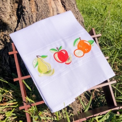 Toalha branca bordada com frutas sobre suporte de madeira ao ar livre