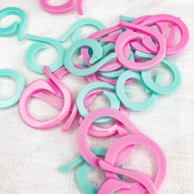 Argolas de plástico rosa e verde água sobre tecido branco