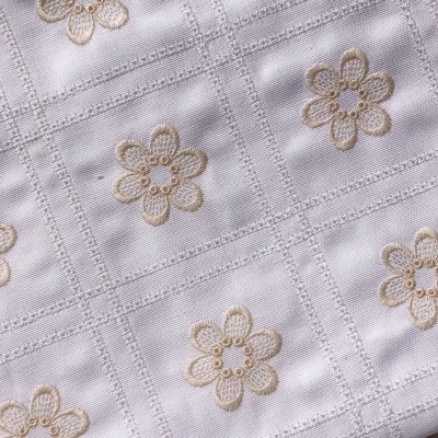 Tecido branco bordado com flores bege em padrão quadrado