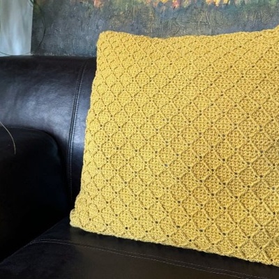 Almofada amarela texturizada num sofá de pele preto