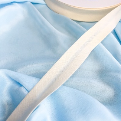 Fita adesiva branca de tecido sobre tecido azul claro com rolo ao lado