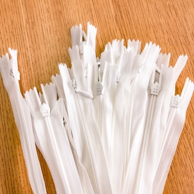 Vários fechos éclair brancos agrupados sobre superfície de madeira clara