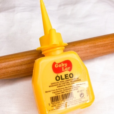 Frasco amarelo de óleo lubrificante Gaby Lar com tampa de bico fino e texto em português