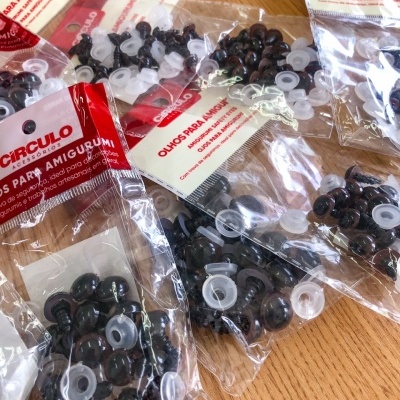 Pacotes com olhos de segurança para amigurumi da marca Círculo sobre mesa de madeira.