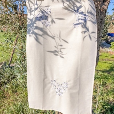 Saia branca bordada pendurada numa árvore ao ar livre