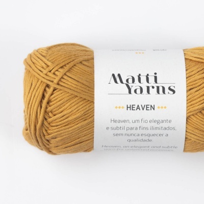 Novelo de lã amarelo mostarda com etiqueta branca e texto em português