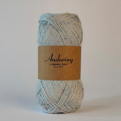 Novelo de fio azul claro com rótulo castanho e texto preto sobre fundo branco