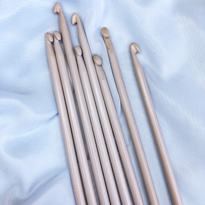 Agulhas de crochet em madeira de vários tamanhos sobre tecido branco