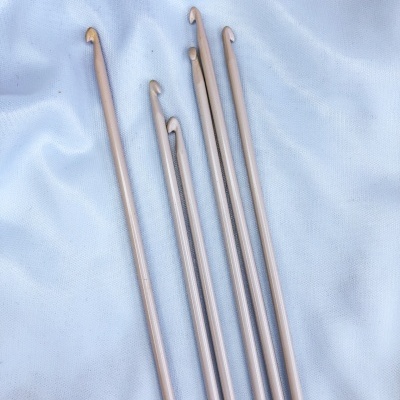 Seis agulhas de crochet metálicas prateadas sobre tecido branco