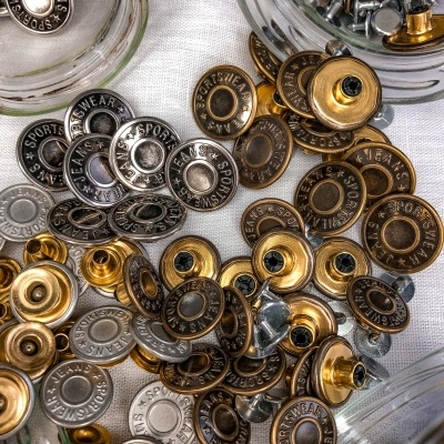 Botões metálicos coloridos e parafusos sobre superfície branca