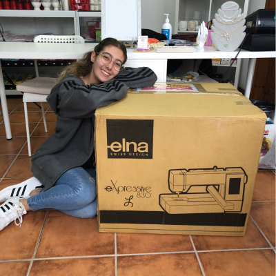 Caixa de máquina de costura elna e jovem sentada no chão da loja