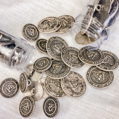 Moedas metálicas prateadas com inscrições U.S. NAVY PACIFIC espalhadas sobre tecido branco