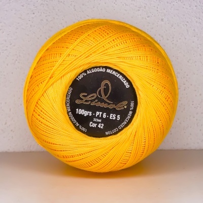 Novelo de linha amarela em algodão mercerizado com etiqueta preta no centro