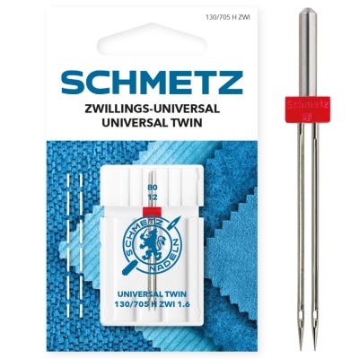 Agulhas de costura duplas SCHMETZ numa embalagem branca com texto azul sobre tecido azul