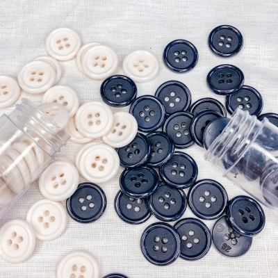 Botões redondos bege e pretos em tecido branco com frascos plásticos