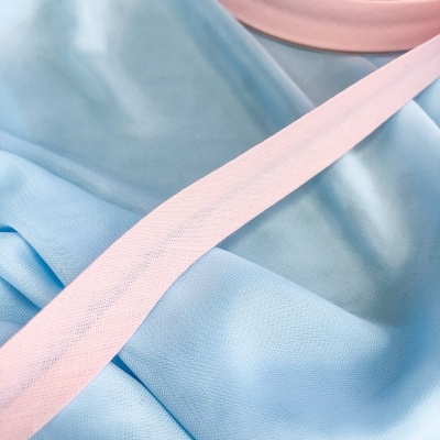 Fita de tecido cor-de-rosa num rolo sobre tecido azul claro