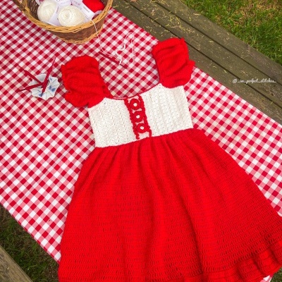 Vestido de crochet vermelho e branco sobre toalha xadrez
