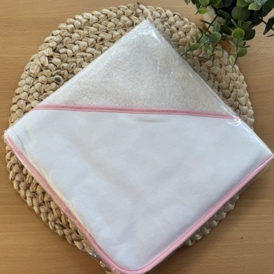 Toalha de bebé branca com borda rosa sobre tapete de fibras naturais