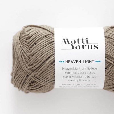 Novelo de fio bege claro da Matti Yarns com etiqueta Heaven Light em fundo branco.