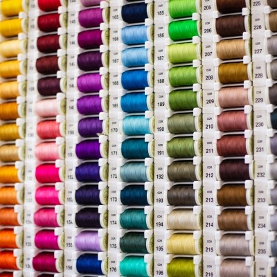 Rolos de linha de várias cores organizados em suportes plásticos com números visíveis