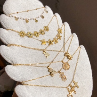 Colares dourados com pendentes variados expostos em suporte branco em forma de mão