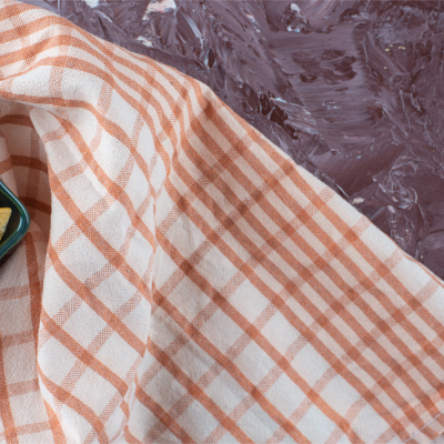 Pano de cozinha xadrez rosa com tigela verde e batatas fritas.