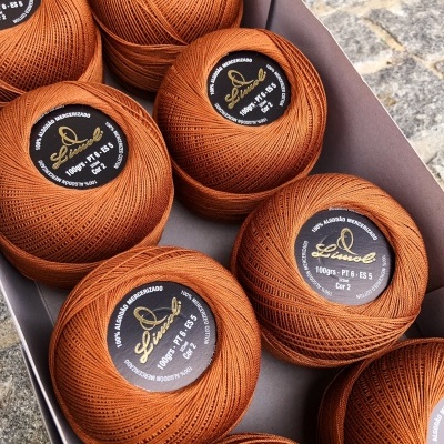 Bolas de linha de algodão mercerizado castanho alaranjado numa caixa