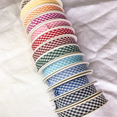 Rolos de fita decorativa xadrez em várias cores sobre tecido branco