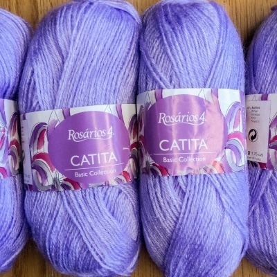 Novelos de lã lilás claro da marca Rosários 4 Catita Basic Collection sobre madeira
